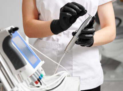 Dentist hands holding endodontic endomotor handpiece.